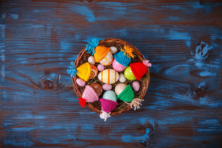复活节篮子里装满了五颜六色的鸡蛋，放在蓝色的木制背景上