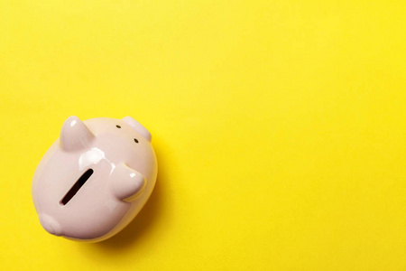 储蓄投资预算财富退休金融货币银行理念。 粉红色储蓄罐隔离在黄色五颜六色的现代时尚背景上。 平躺顶视复印空间
