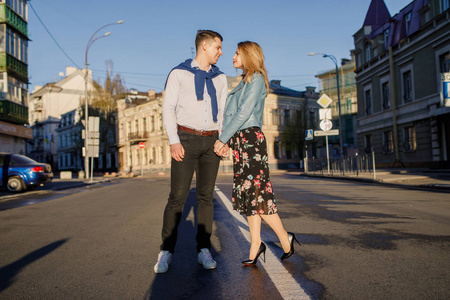 年轻时尚的情侣摆在阳光明媚的街道上