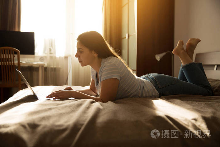 女孩躺在床上看着笔记本电脑照片-正版商用图片192pyj-摄图新视界