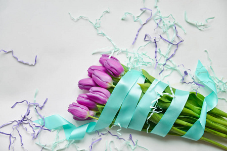 郁金香与蓝色丝带和节日五彩纸屑在一个孤立的白色背景节日花束的生日, 3月8日, 婴儿淋浴, 母亲节, 妇女日。植物区系成分