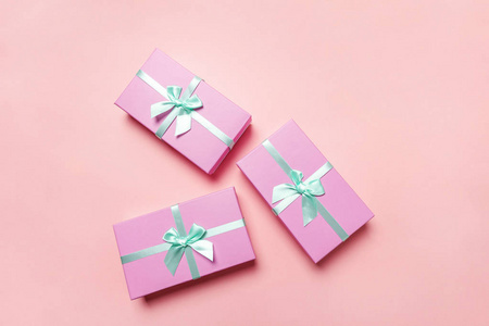 圣诞节新年生日情人节庆祝礼物浪漫的概念。 三个小礼品盒包着粉红色的纸，孤立在粉红色的糊上，五颜六色的时尚背景。 平躺顶视复印空间