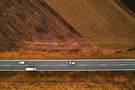 汽车和卡车在笔直的道路上，通过平原乡村景观，从无人驾驶的POV空中俯瞰