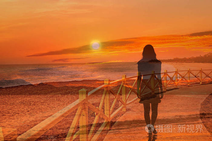 一个女人在美丽的日落时沿着海边散步. 背景是通过双曝光创建的.