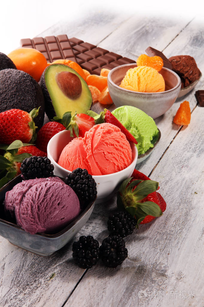 一套不同颜色和口味的冰淇淋勺,桌上有浆果,巧克力和水果