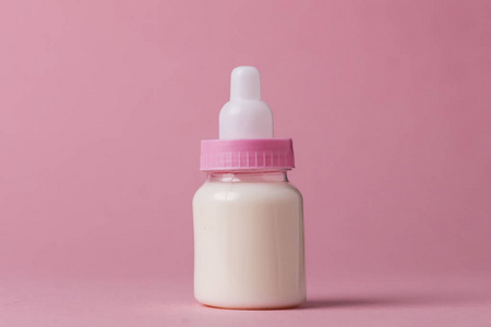 婴儿奶瓶充满牛奶在粉红色的背景
