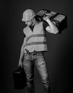 维修服务理念。男子在头盔, 硬帽子持有工具箱和工具, 蓝色的背景手提箱。工人, 修理工, 修理工, 建设者在平静的脸上携带工具箱