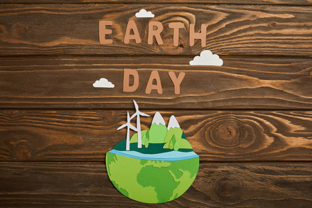 可再生能源剪纸星球的顶部视图和木制背景地球日概念上的纸信