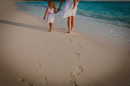 母亲和孩子走在沙滩上留下足迹在沙滩上