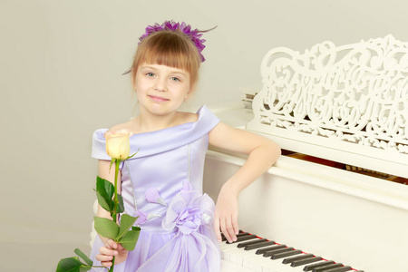 一个女孩在一架白色的大钢琴旁边摆姿势