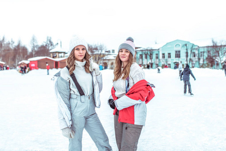 两名女学生摆姿势微笑, 在城市公园的溜冰场上溜冰场。女人休息运动和积极的生活方式。穿着温暖的日常冬衣。概念周末假期在冬季度假村