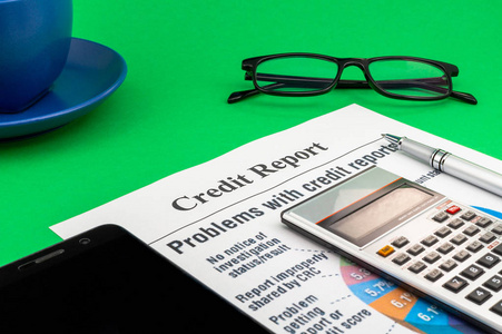 绿色桌笔眼镜咖啡和计算器的信用报告。