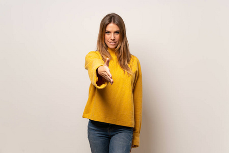 女人穿着黄色毛衣，在隔离墙上握手，为结束一笔好交易