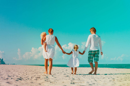 两个小孩的家庭在热带海滩上行走