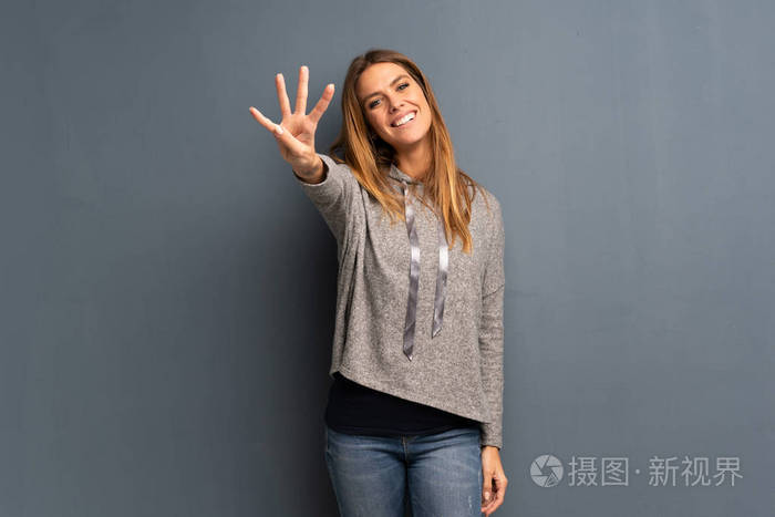 灰色背景的金发女人开心地数着四个手指
