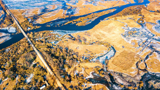 乡村道路和桥梁通过溢流水。 春天融化的河流洪水。 空中全景。 春天的乡村景观。 冰冻的冬季河流。 白俄罗斯