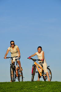 母亲和她骑在自行车上的 dauhgter