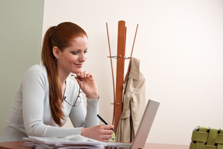 红色的长头发女人在办公室用的笔记本电脑工作