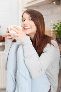 年轻女子在厨房里有咖啡或茶