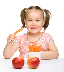 可爱的小女孩吃胡萝卜和苹果