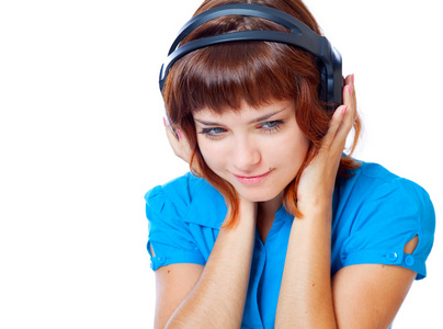 红头发的青年女孩在听音乐的笔记本电脑的耳机