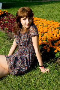 美丽的女孩坐在草地上用鲜花