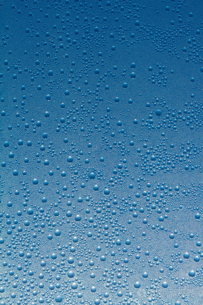 水滴的蓝色玻璃背景上