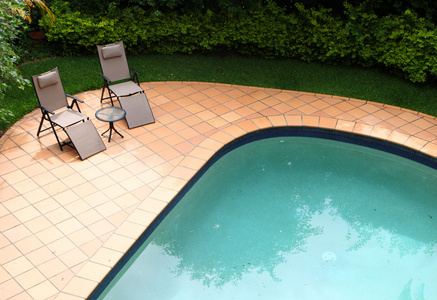 两个活动靠背椅包围的热带花园游泳池