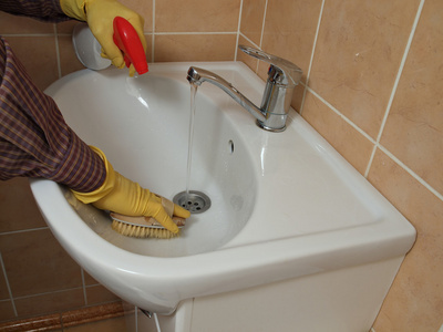 一个人在清洗浴室水槽戴着手套
