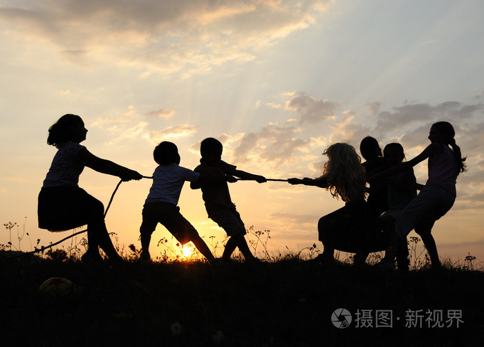 剪影快乐玩耍的孩子们在草地上日落夏季组