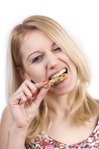年轻女子吃饼干与鬼脸