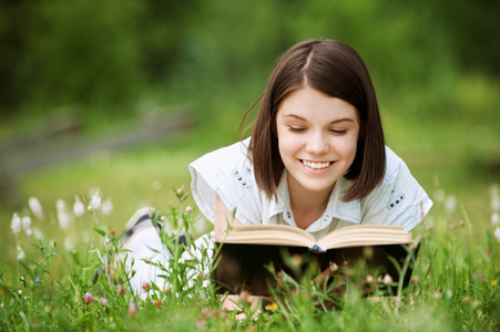 年轻女子躺在草地上和看书