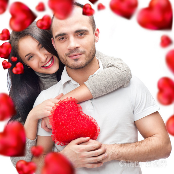 美丽的年轻人爱情侣拥抱反对一个白色背景和飞来飞去他们的许多红色