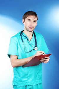 年轻的医生男人与听诊器和蓝色背景上的文件夹