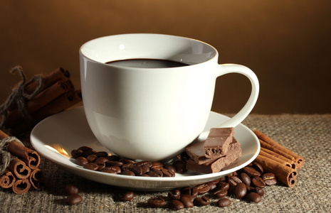 杯咖啡和咖啡豆 肉桂棒和巧克力棕色背景上洗劫