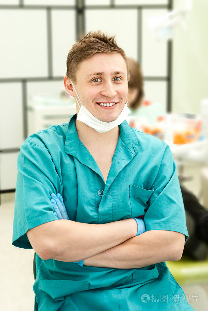 微笑与牙科办事处在背景中快乐牙科医生的肖像