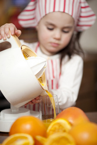制作新鲜和健康的桔子汁的小女孩