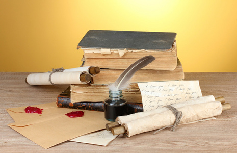老书 卷轴 羽毛笔和墨砚在黄色背景上的木桌上