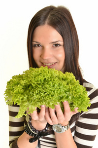 快乐的年轻女人举行绿色生菜和微笑，在白色背景