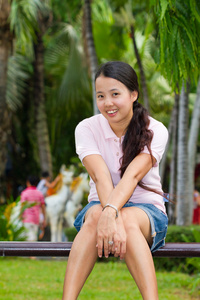 坐在亚洲女人和在长凳上的微笑