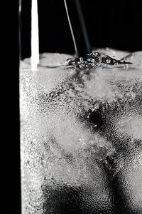 杯水和黑色背景上的冰