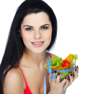 一个年轻漂亮的女人吃蔬菜沙拉孤立在白色背景上的肖像