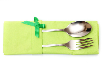 叉子和勺子在带有隔离在白色蝴蝶结绿布