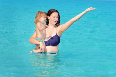 快乐的孩子与她的母亲在海滩上