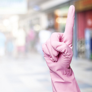 女人与粉红色手套打手势反对拥挤的地方 照片