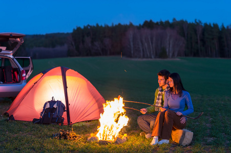 帐篷露营车夫妇坐在篝火旁