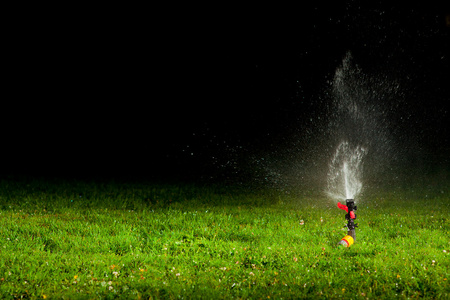在晚上把水洒在绿草的草坪洒水