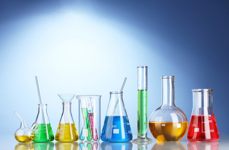 不同实验室玻璃器皿与颜色液体和蓝色背景的思考