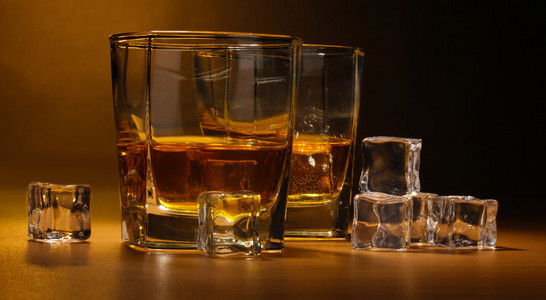 两个眼镜的苏格兰威士忌和棕色背景上的木桌上的冰