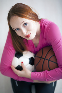 美丽的金发女孩举行足球和篮球球